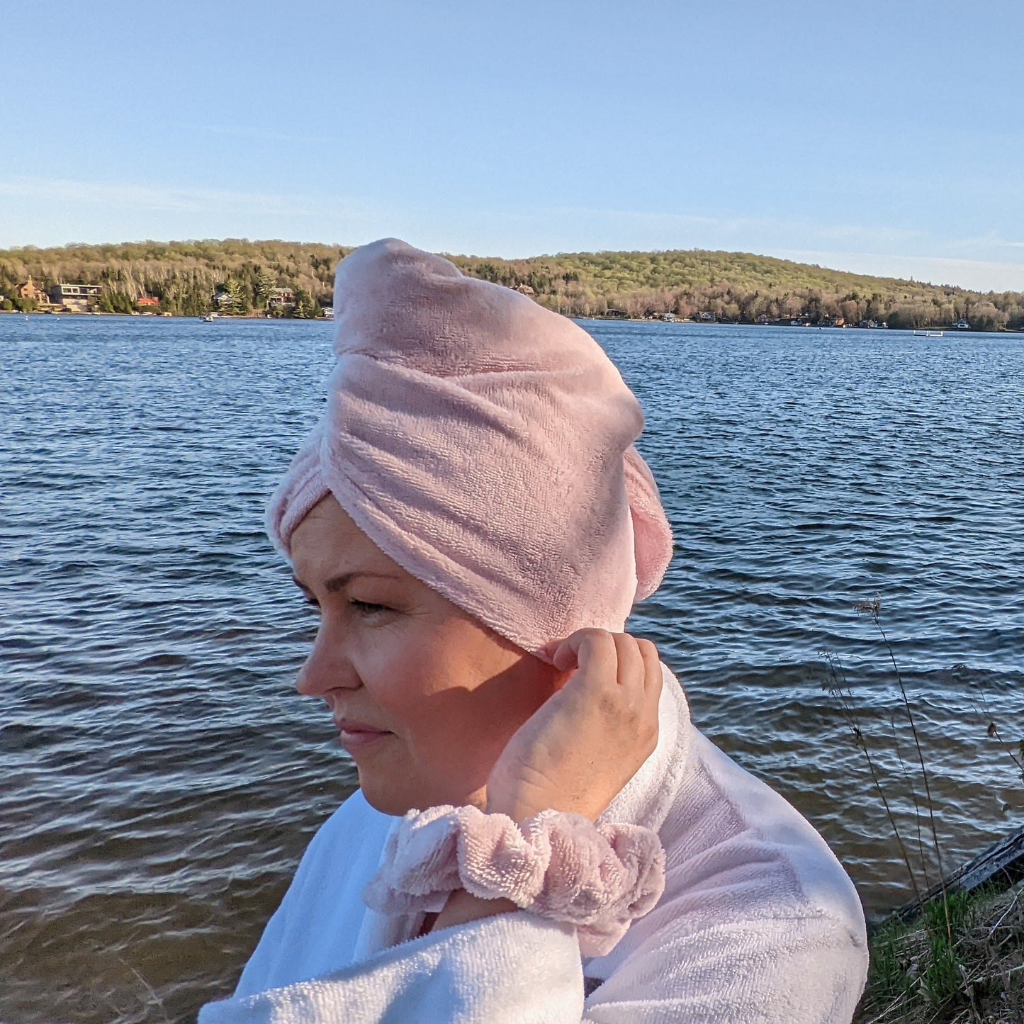 woman wearing pink hair towel and drying her hair at the cottage, she is wearing a matching pink blush scrunchie on her wrist